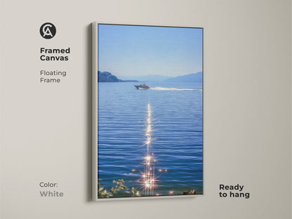 White framed canvas featuring a boat on blue water. The sparkling ocean artwork is a realistic lake landscape. Ready to hang and will enhance coastal bedroom wall decor for boat lovers. Summer water scene art as nautical home decor. Modern boat artwork for calm spaces.