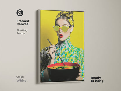 Framed canvas in a white floating frame displaying a pop art woman eating noodles. Ready to hang this artwork brings a colorful and eclectic touch. The vibrant yellow backdrop enhances the retro style. Perfect for kitchen decor.