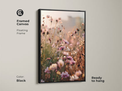 Framed canvas with a floating black frame showcasing wildflower artwork. Ready to hang this botanical bedroom decor features soft pinks and peach tones. The impressionistic canvas adds a touch of nature and elegance to any space.