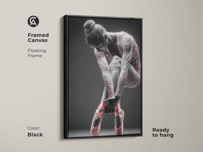 Framed canvas artwork featuring a ballerina. This canvas has a floating frame. The frame color is black. The art features a ballerina tying her pink ballet shoes. This framed art is ready to hang.