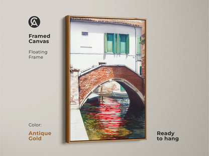 This framed canvas print captures a Venice canal with a brick bridge and red reflections. The antique gold floating frame adds elegance to the traditional artwork. Ready to hang for a sophisticated wall decor.