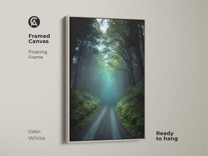 Framed canvas art featuring a misty forest road in a white floating frame. This dark green and teal nature landscape evokes a rustic woodland feel. Ready to hang this artwork features foggy trees. It creates a serene forest scene in any room. Perfect as a housewarming gift