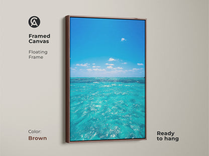 Framed canvas of turquoise ocean waves with a brown floating frame. This blue water sky landscape painting offers a realistic seascape. Enhance your living space with this nautical bedroom decor.