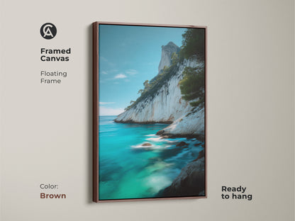 Brown framed canvas featuring coastal cliff canvas print of azure ocean. The turquoise blue beach art shows the rocky coast landscape art. The framed floating frame is ready to hang this piece is perfect as housewarming gift art.