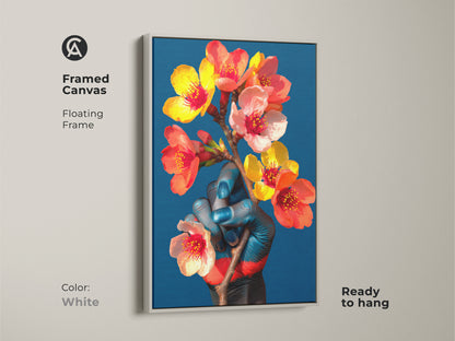 Eclectic botanical artwork in a white floating frame. The canvas features a blue hand holding delicate orange and red flowers. This surreal art print adds a modern touch to any room ready to hang.