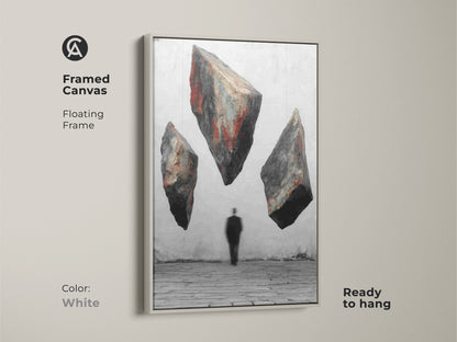 White framed canvas art features floating textured rocks and a man in a suit. This red black gray artwork is a conceptual piece for your wall. The floating frame adds a modern touch. Ready to hang as an unusual wall hanging. Makes a unique statement in your home decor.