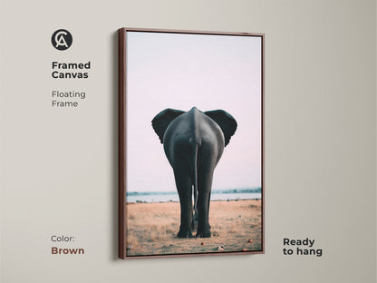 Brown framed canvas print of an elephant rear view. This safari wildlife canvas print is ready to hang. The floating frame enhances the photorealistic elephant art. The contemporary animal decor suits any space. This minimalist savanna art piece brings nature into your home. Perfect as a housewarming gift.