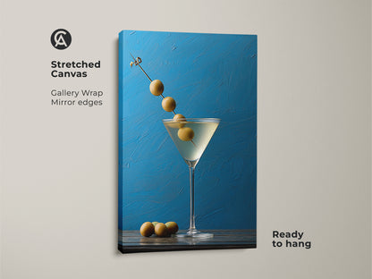 Stretched canvas showcasing a martini still life artwork with olives. The gallery wrap features mirror edges. This blue cocktail wall art is ready to hang. It will make a stylish addition to modern kitchen decor. This contemporary bar art is perfect for art for cocktail lovers.