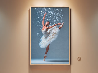 Framed ballerina canvas art. Ballerina in a white tutu. She is en pointe with one leg extended high. White feathers accent the artwork. The frame is a light wood color. This beautiful ballet art is ready to hang and enjoy.