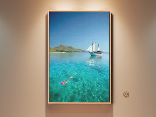 Turquoise ocean canvas print features a sailboat. A snorkeler swims in the clear tropical water. This coastal artwork brings a beach house vibe. A perfect travel gift or nautical decor piece.