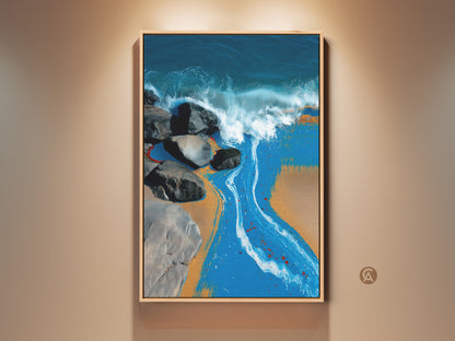 Coastal abstract wall art displayed in a modern frame. The artwork shows deep blue ocean waves crashing against rocks on a sandy beach. It adds a splash of color and artistic flair to any space.