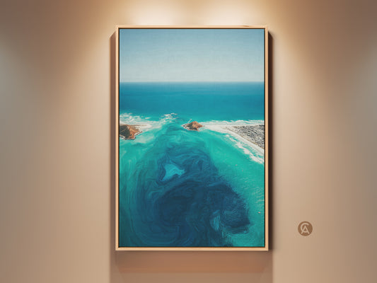 Framed aerial ocean abstract canvas print. This turquoise coastal landscape wall art features deep blue swirls. The beach house decor is a perfect gift for the home. This wall art adds a modern touch.