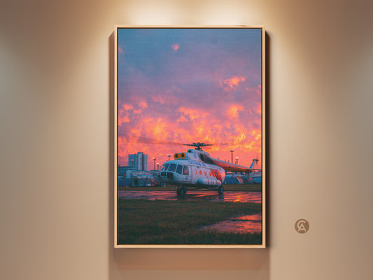 Framed aviation artwork. A helicopter is parked on the tarmac. The sky is a mix of blue and fiery orange at sunset. This framed canvas adds a touch of aviation history to any room.