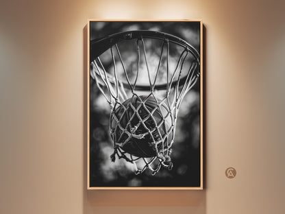 Framed basketball art in a room setting. The artwork is matted with a thin frame. It features a basketball swishing through a net. The black and white photo gives a classic look. Decorate your space with sports-themed wall decor.