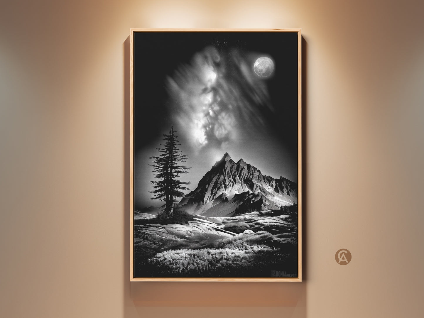 A framed monochrome mountain art print hangs on a wall. This black and white landscape features a moonlit pine tree under a cloudy sky. It brings contemporary nature artwork to a home office.