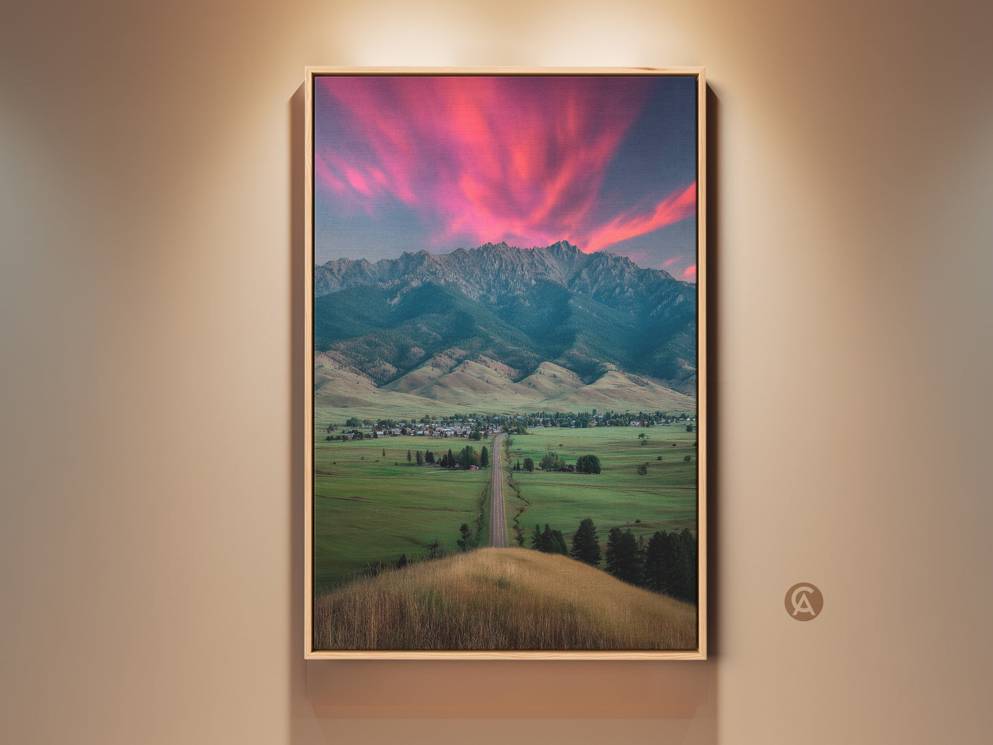 Framed pink sunset mountain canvas art displayed indoors. The landscape wall art brings a touch of modern farmhouse decor to any room. Ideal as scenic bedroom wall art. Perfect as a housewarming gift for outdoor lovers. It adds a rural town charm to residential wall decor
