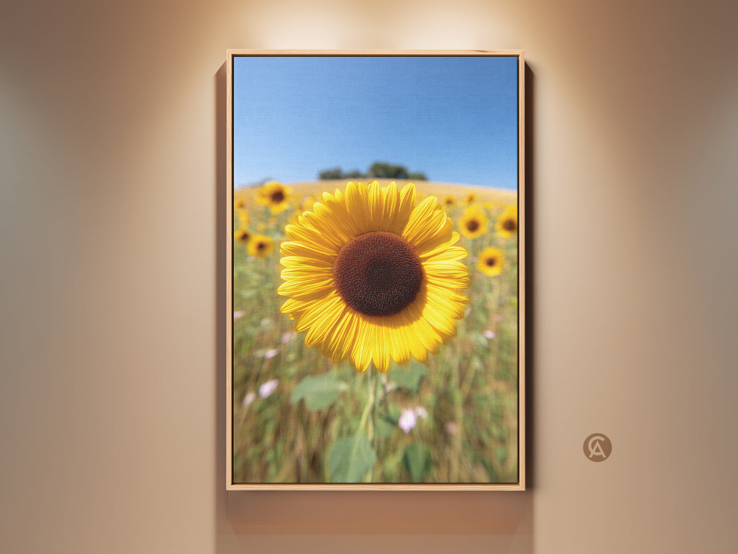 Framed sunflower field canvas artwork hangs on a beige wall. This yellow floral landscape print captures a sunny summer day. A rustic farmhouse decor piece that brings nature's artistry indoors. A perfect gift for grandma who loves botanical art and outdoor scenes.