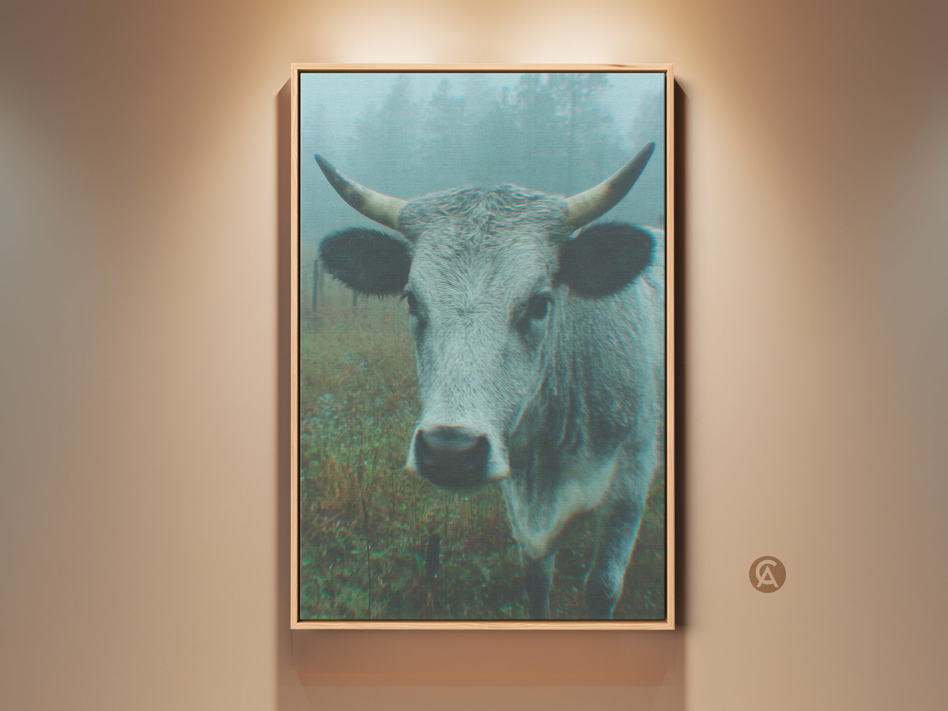 Framed canvas print featuring a cow in a misty field. The artwork has a modern style. Displayed on a beige wall with a warm spotlight. Perfect for rustic home decor.