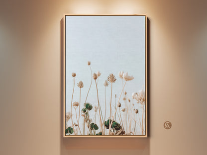 Framed boho wildflower art print in cream and light blue tones. The minimalist floral artwork enhances bedroom decor. A serene botanical piece brings nature indoors. Perfect as a housewarming gift for plant lovers.  It is ideal for minimalist interiors. This canvas print adds a delicate artistic touch to residential spaces.