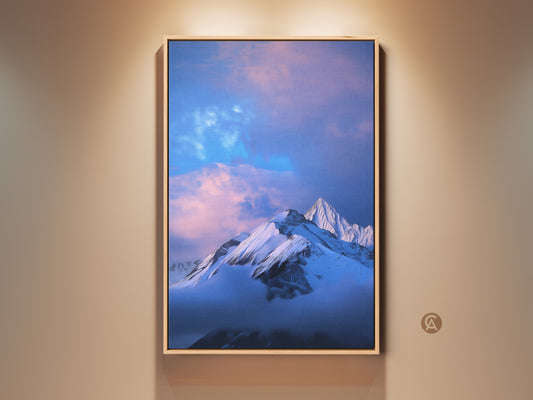 Photorealistic snowy mountain artwork in a wood frame. The winter sky has blue and pink hues. This canvas art print brings nature indoors. Perfect modern wall decor for bedrooms. A great gift for outdoor lovers.