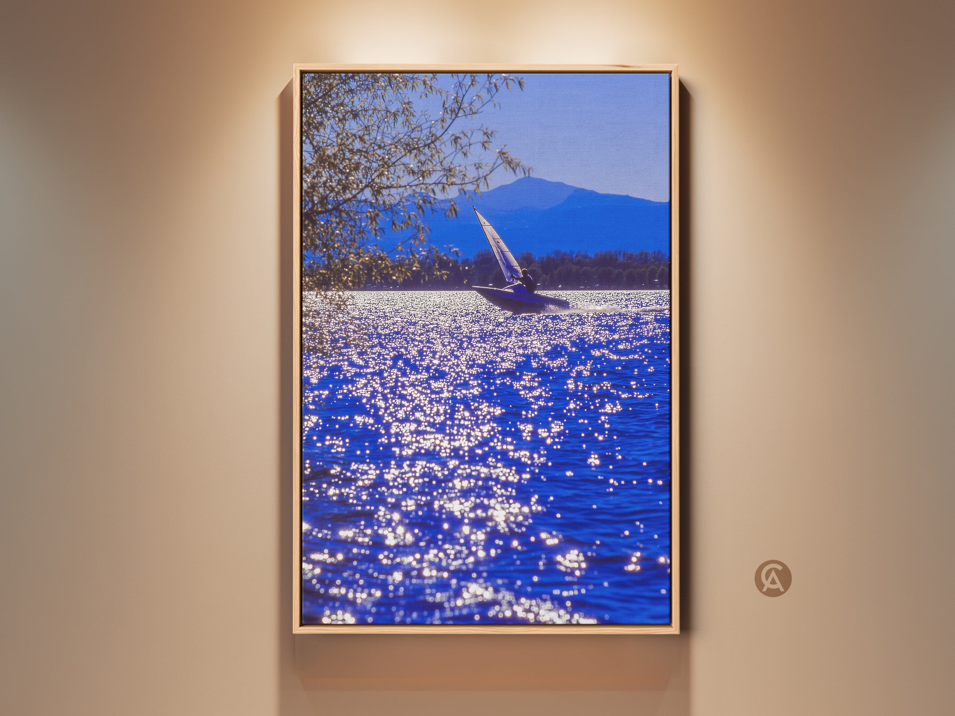 Realistic sailboat art print displayed in a residential setting. The deep blue water sparkles. A mountain range is visible in the distance. It is a contemporary coastal art piece for home or office spaces.