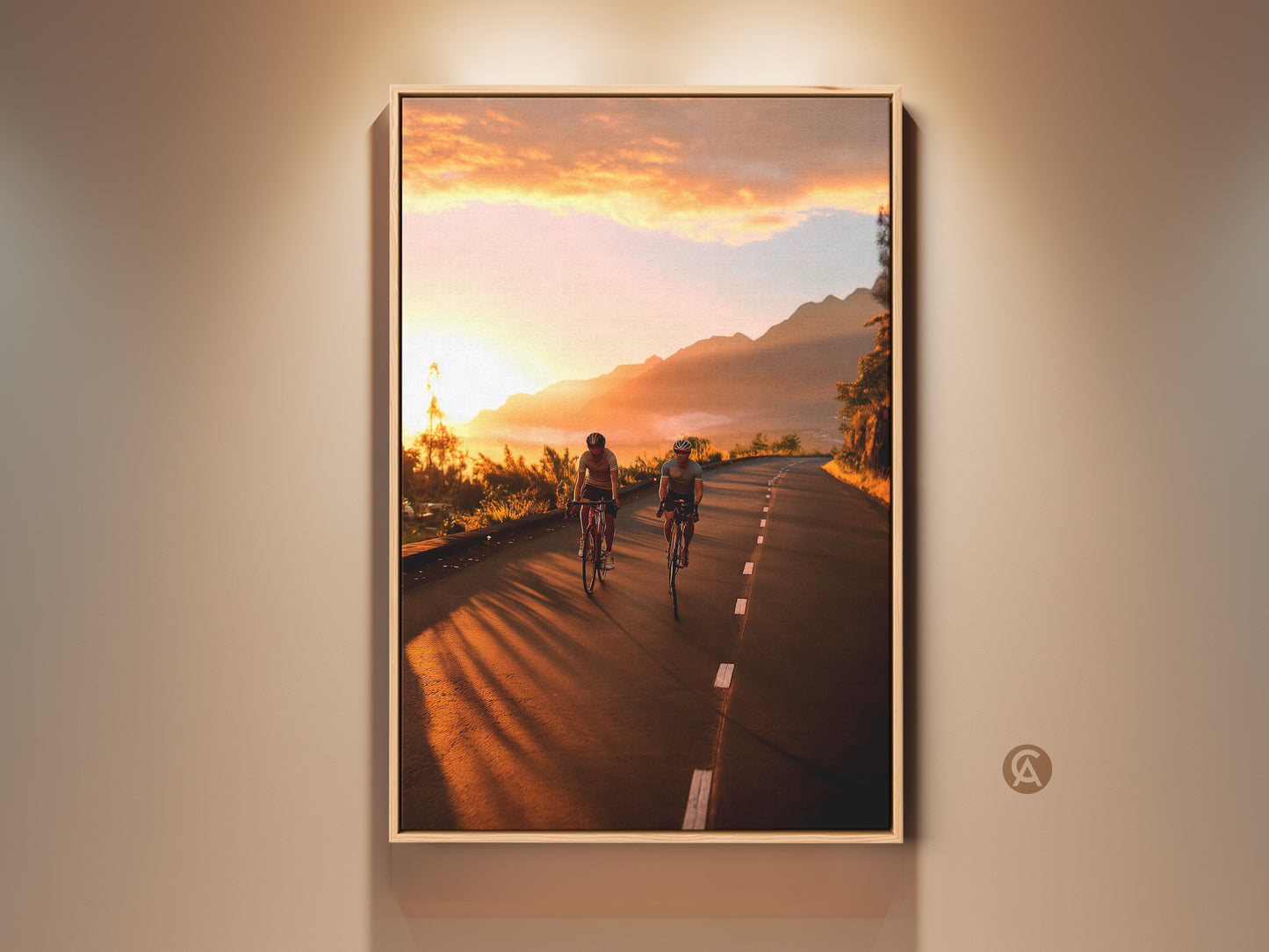 Cycling wall art print featuring a mountain road at sunset. The warm yellow and orange sky creates a golden hour glow. This landscape photography captures the thrill of adventure. It is a perfect gift for cyclists and travel enthusiasts. Enhance your home with this motivational wall art.