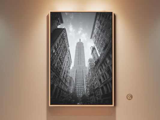 Framed black and white artwork of the Empire State Building. The art is displayed in a wooden frame. A worm's eye view shows the full height of the iconic New York City skyscraper.
