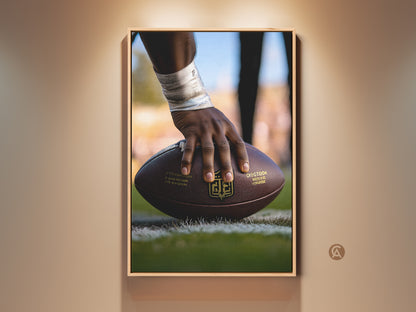 American Football Action Shot Canvas Print. A player's hand powerfully grips the football. The brown leather contrasts beautifully with the gold accents. Ideal art for a man cave or office. This modern sports artwork is a perfect gift for him. Elevate your space with this athletic canvas art.