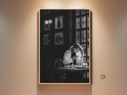 Monochrome cafe scene wall art. This contemporary black and white photojournalism style print features a woman with coffee. It's perfect dining room decor. The artwork brings a sophisticated lifestyle aesthetic to any contemporary space. It makes a thoughtful gift for coffee lovers and housewarming occasions.