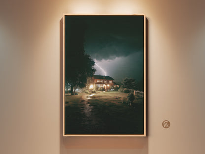 Modern wall art shows a house lit by a dramatic lightning strike. This atmospheric nature artwork features a dark blue sky and yellow lightning. A unique landscape print great as a homeowner gift adding beauty to residential landscape decor