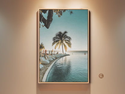 Framed tropical palm tree wall art. A coastal infinity pool canvas print brings beach ocean views. Relaxed home decor gift idea. This artwork features serene aqua and blue tones. Perfect for adding a vacation paradise ambiance to your living space.