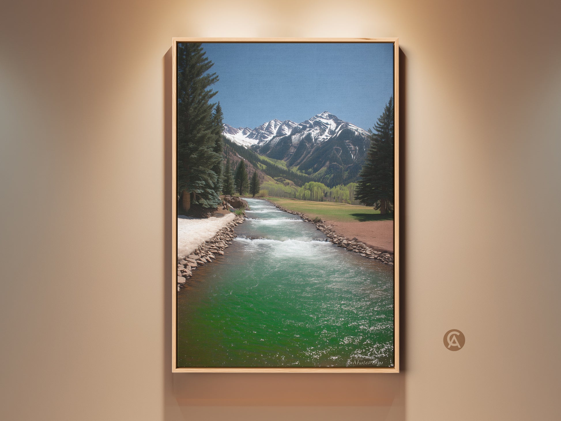 Rustic mountain river landscape canvas art is framed in natural wood. Turquoise blue green river creates a tranquil scene. Snow capped mountains rise above pine trees. Perfect wall art for nature and outdoor lovers.