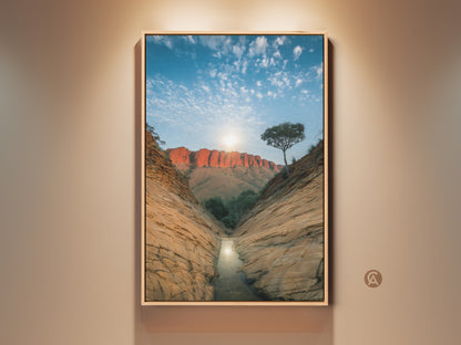 Experience the beauty of Australian desert canyon wall art. This canvas print showcases a red rock landscape bathed in sunlight. A perfect piece for entry hall decor or a unique travel themed gift. This nature photography brings the outback to your home with orange and blue tones.