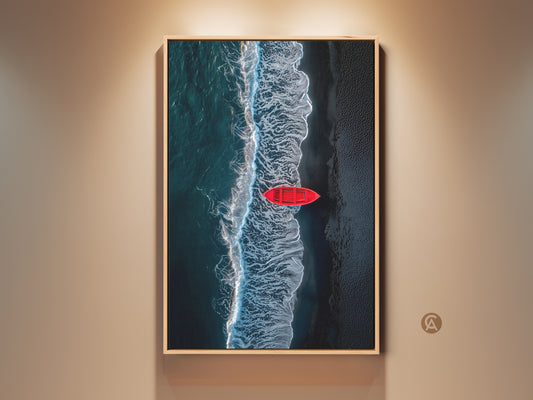 Framed aerial beach art print. A red rowboat sits on the shore. Waves are crashing next to it. The frame is light wood. This ocean artwork adds coastal charm to any room.