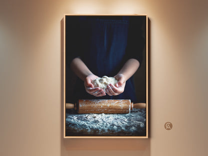 Rustic kitchen wall art features hands holding dough. A wooden rolling pin rests below. The beige and brown tones create a cozy farmhouse feel. Perfect housewarming gift baker.