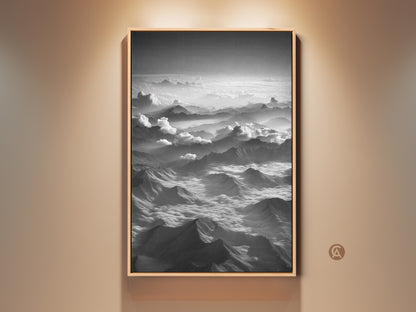 Framed aerial mountain canvas art in black and white. It is a minimalist cloudscape wall decor piece. This contemporary nature artwork features a black frame. Perfect modern home office art.