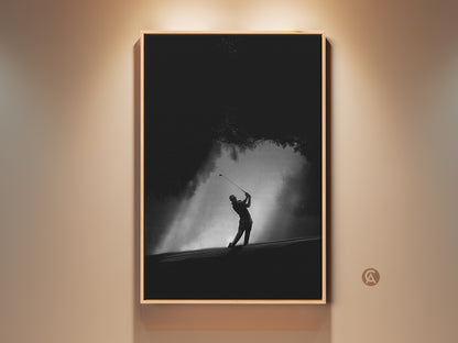 Dramatic black and white golf art print. A golfer is captured mid-swing in a powerful pose. The artwork is framed in a warm wood tone. Perfect for golf enthusiasts or a modern home decor statement.