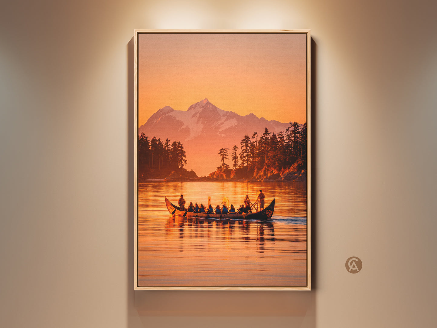 Framed canvas artwork featuring a pacific northwest canoe scene. The artwork shows a canoe with people on a lake. A snow-capped mountain and forest are in the background. Warm sunset colors fill the sky. This framed wall art brings nature indoors.