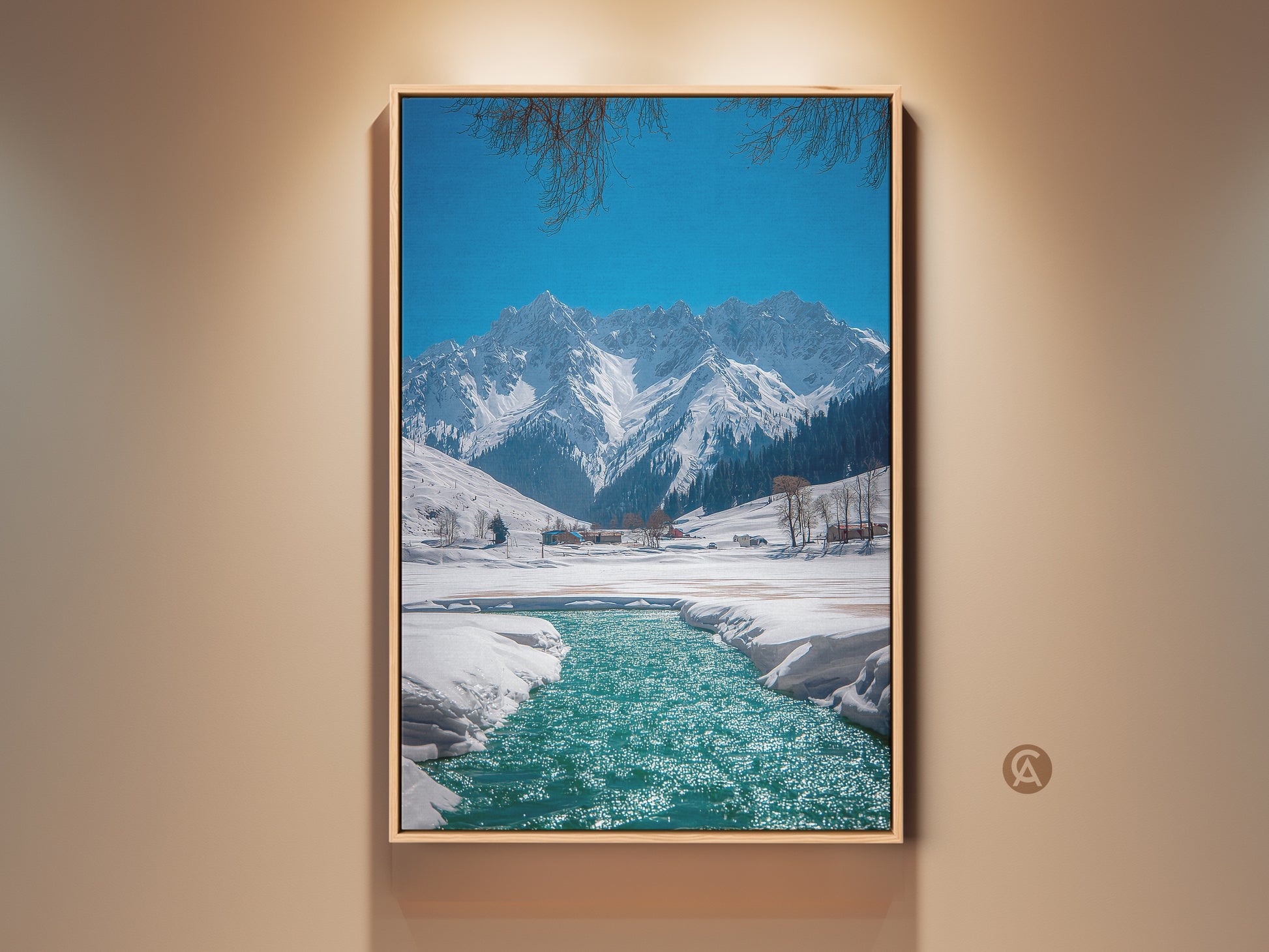 Rustic winter landscape artwork displays snow-capped mountains and a teal blue river. A scenic canvas print of nature with a clear blue sky and branches at the top of the frame. Perfect nature wall decor for outdoor enthusiasts a peaceful mountain view.