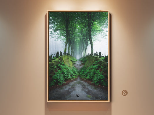 Framed misty forest path canvas art is displayed on a wall. This emerald green tree-lined road is a Scandinavian woodland landscape. This nature wall decor is a perfect gift. The artwork evokes tranquility. It enhances any room with a touch of nature's beauty.