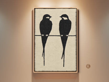 Framed minimalist bird artwork in a modern setting. Two black bird silhouettes perch on a wire against a textured cream background. This Scandinavian-style canvas art is a perfect gift for bird lovers. The artwork adds a calming presence to any room. Ideal for a contemporary home decor.