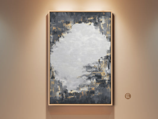 Framed charcoal grey and gold abstract artwork hangs on a neutral wall. This contemporary canvas art features textured brushstrokes. It's perfect for adding a sophisticated touch to a living room or office. The neutral color palette complements various decor styles making it a versatile piece.