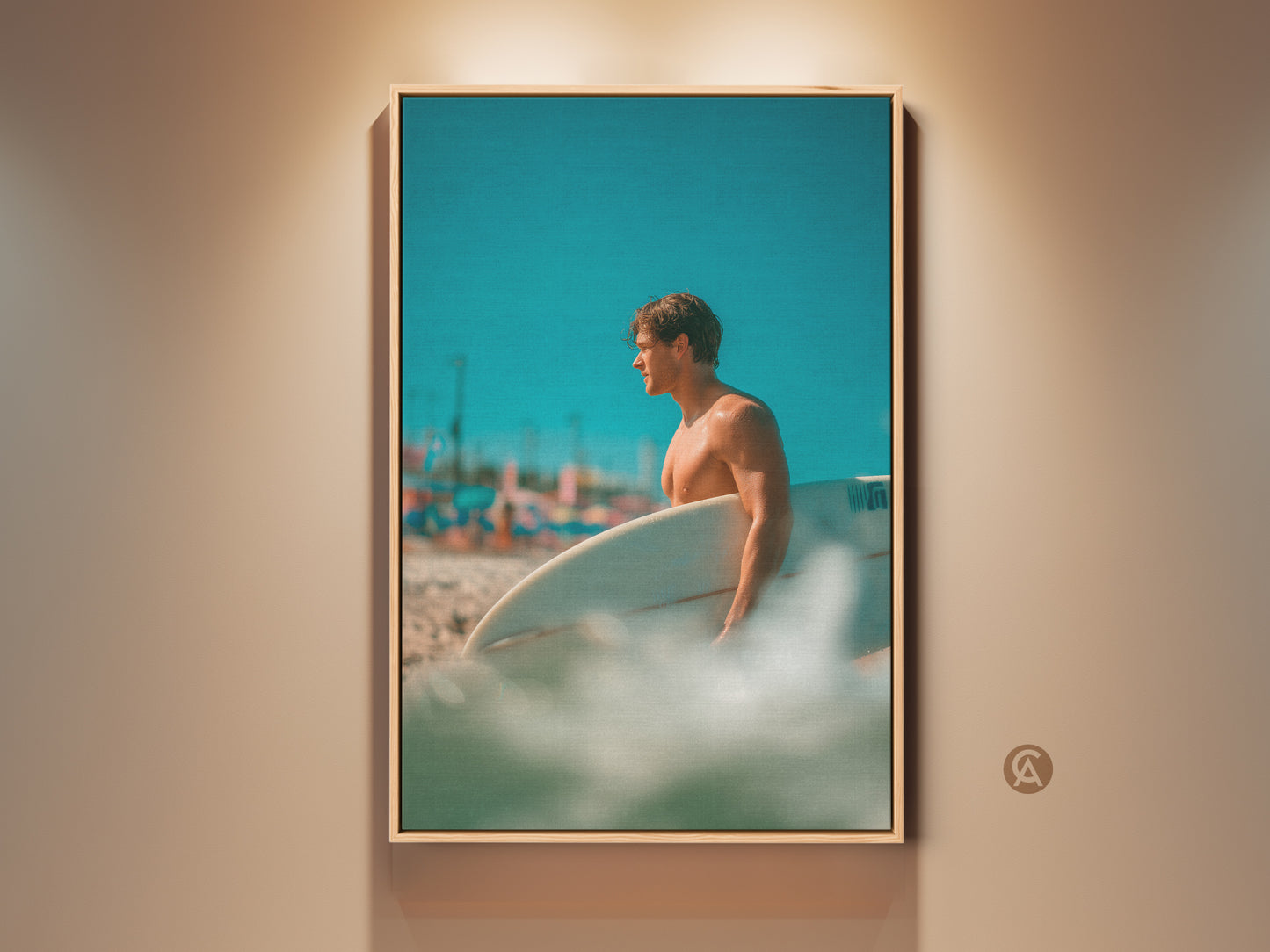 Framed artwork featuring a surfer. The surfer is holding a surfboard on a sunny beach. The artwork is brightly lit. The frame around the art is oak color. The perfect piece for a beach lover.