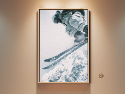Framed artwork featuring a skier in mid-air. The skier is wearing white gear. The artwork has a natural wood floating frame. A great piece for sports enthusiasts. Ready to hang and enjoy.