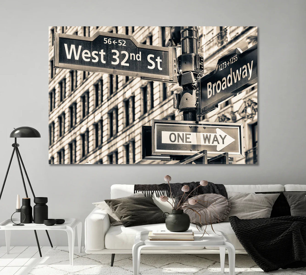 Sepia-toned New York street signs canvas print styled above a light modern sofa.